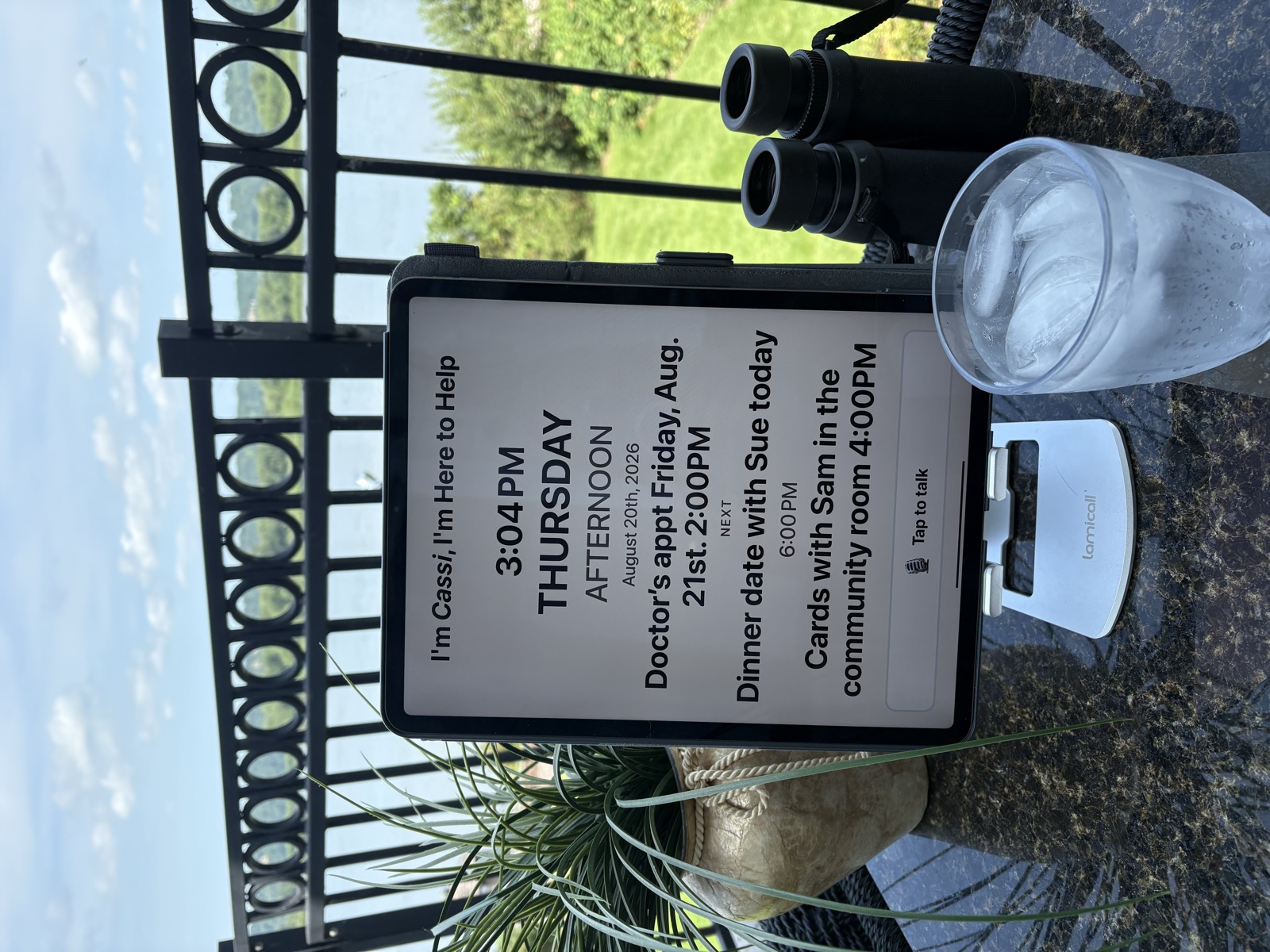 The Compasse board on a patio table overlooking a lake, showing Thursday afternoon, dinner with Sue at 6, and cards with Sam at 4